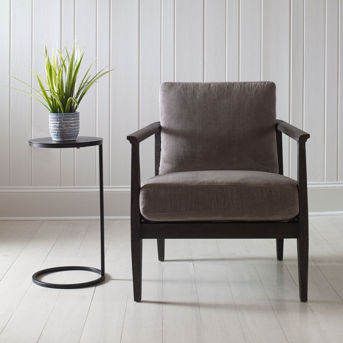 Gray armchair in a room with a small table and plant