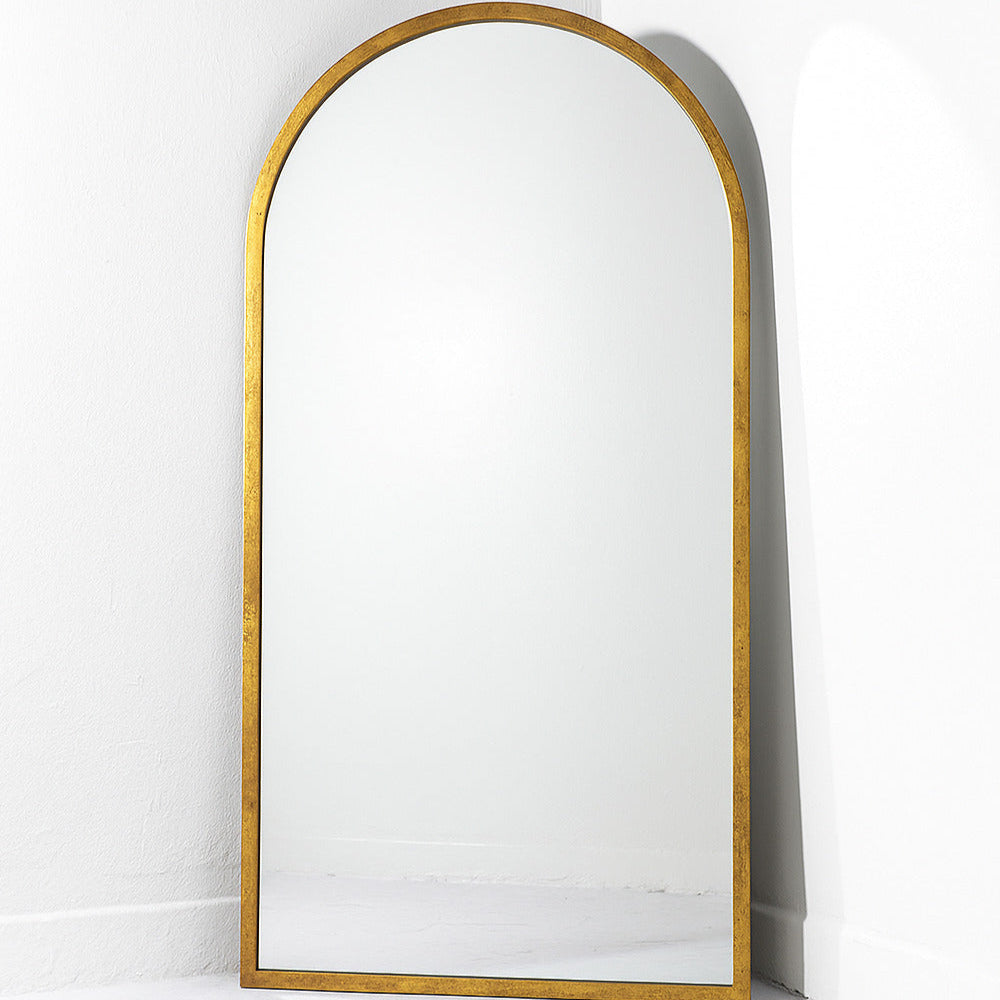Gold-framed arch mirror on a white wall