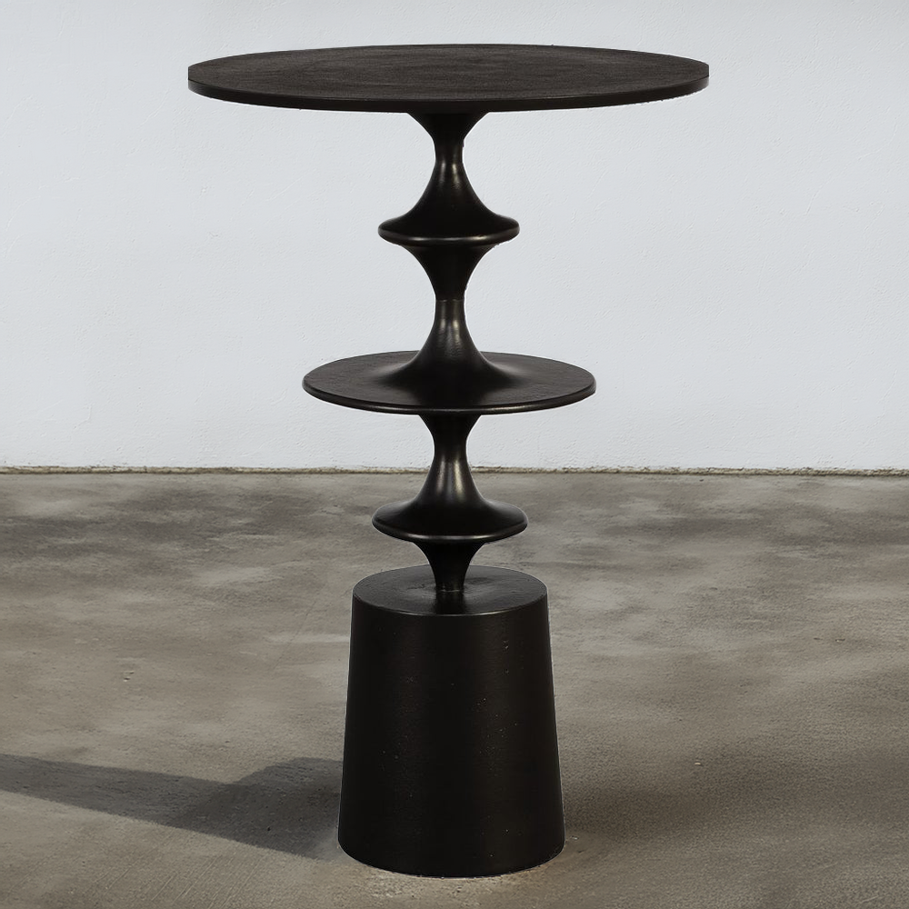 Round black metal accent table on a concrete floor and white background.