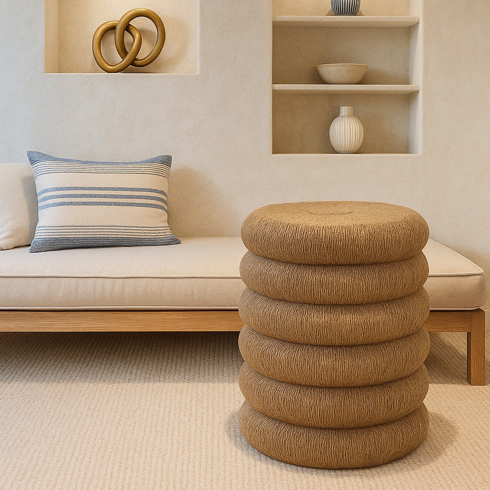 Modern interior with a beige sofa, striped pillow, and textured stool.
