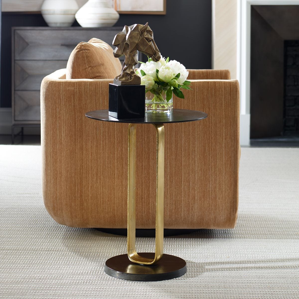 Modern side table with gold legs and black top in a living room setting.