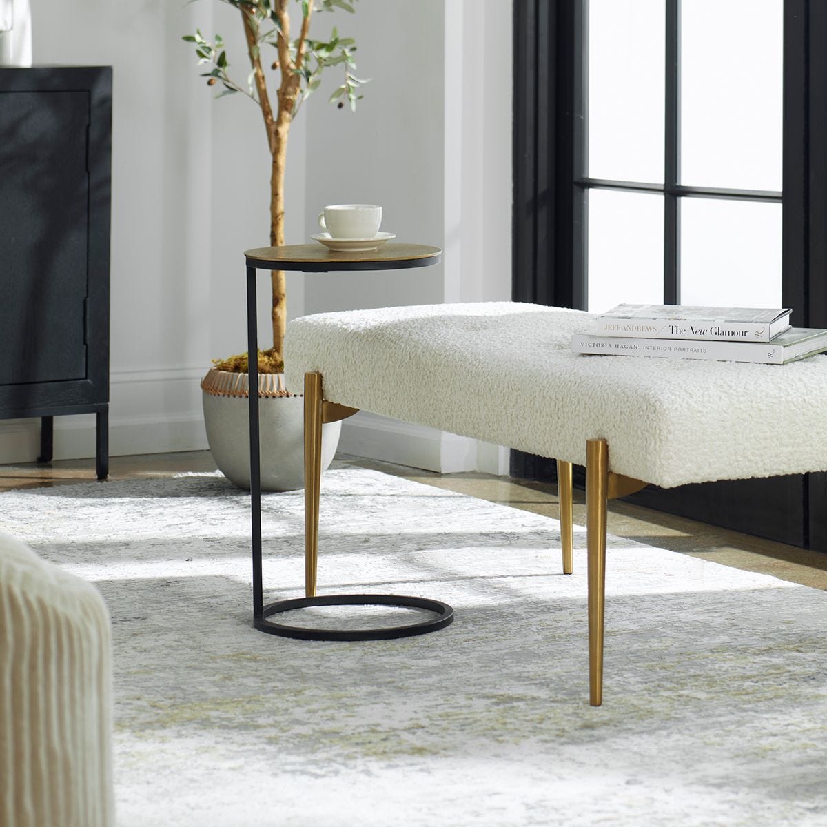 Modern living room with a white ottoman, side table, and decor items.