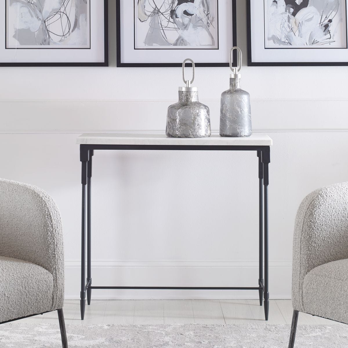 Small black metal table with decorative items in a room with framed art on the wall.