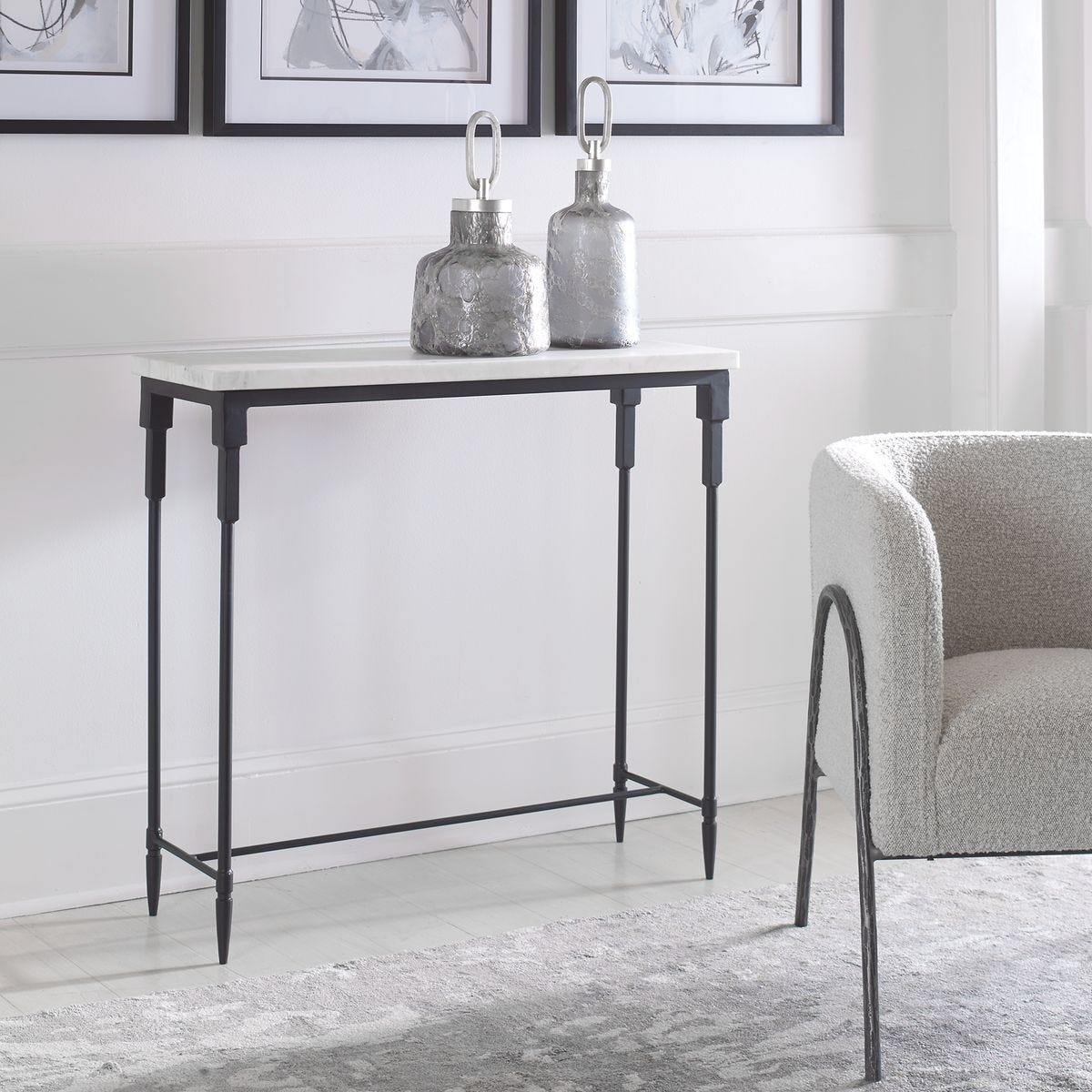 Small table with marble top and metal frame in a room with a chair and framed pictures on the wall.