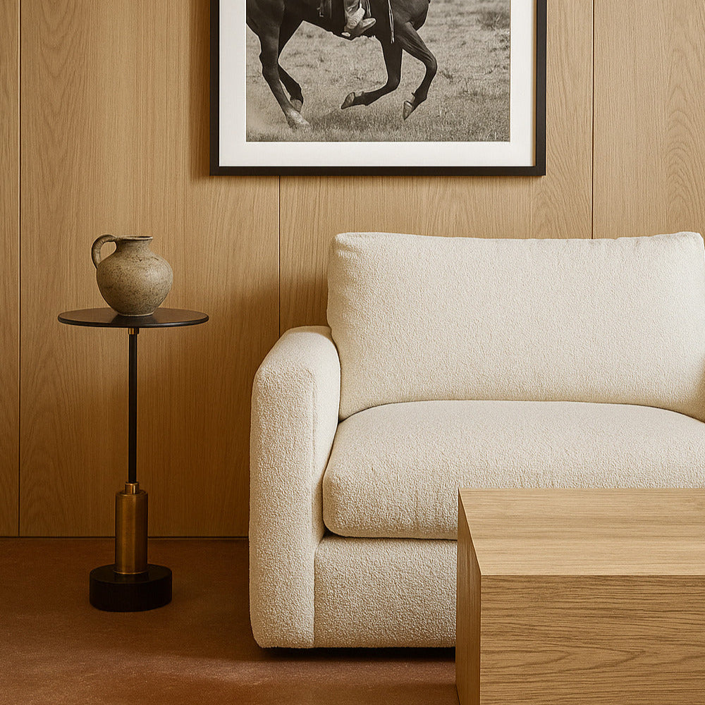 Framed black and white photograph of a cowboy on horseback above a beige sofa in a room with wooden walls.