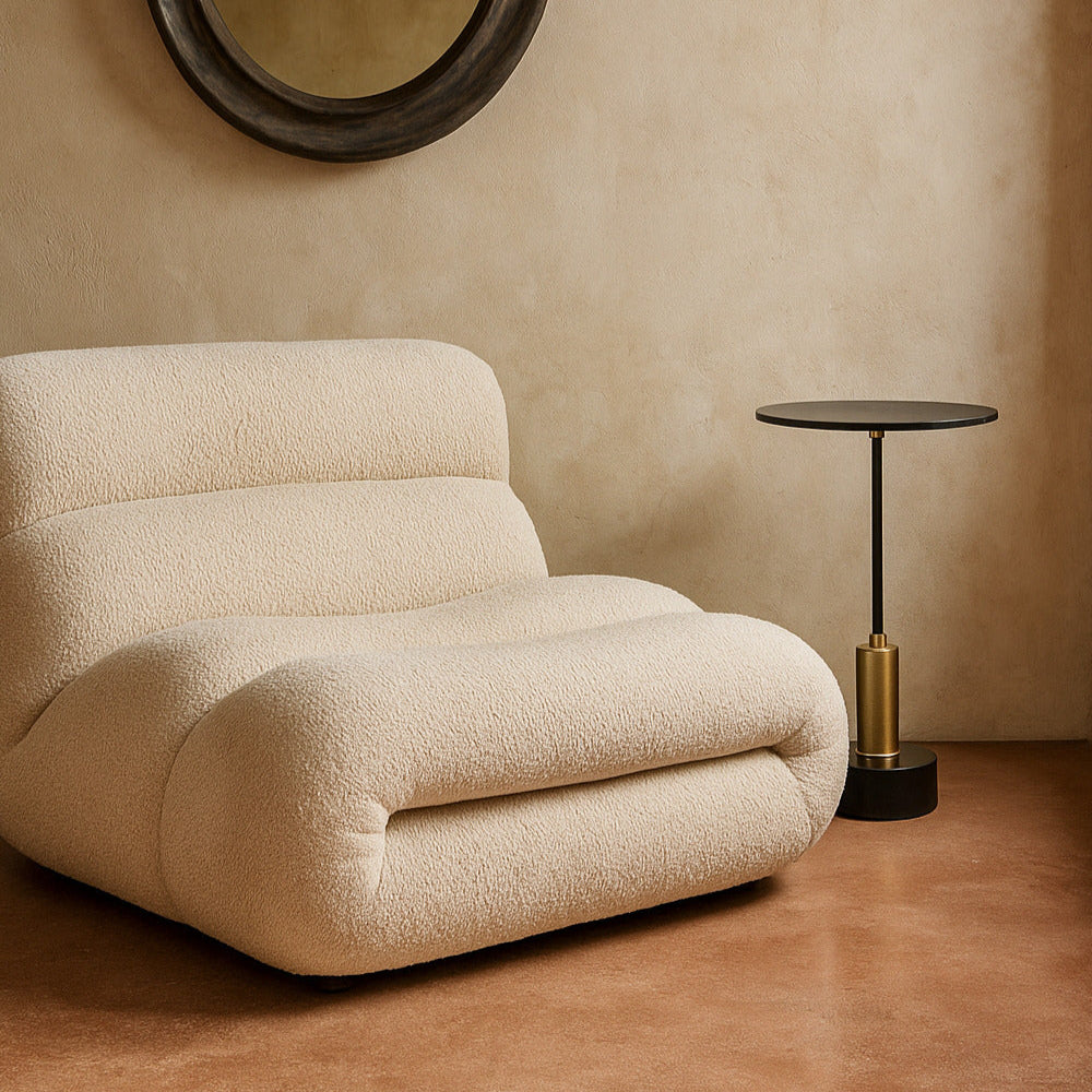 Beige armchair in a room with a round mirror and small table.