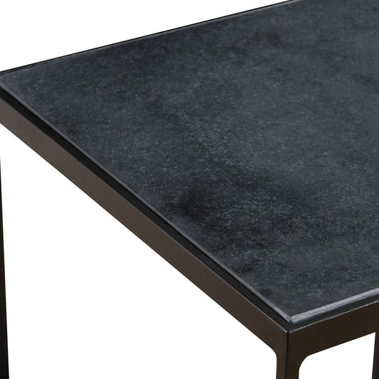 Modern chair with a metal frame and wooden seat next to a small table against a neutral wall.