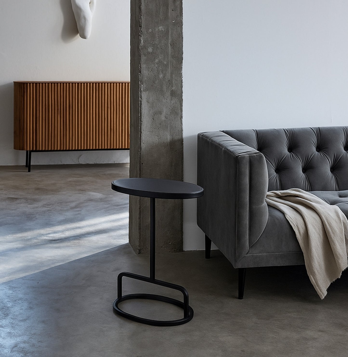 Modern living room with a black side table, gray sofa, and wooden cabinet.