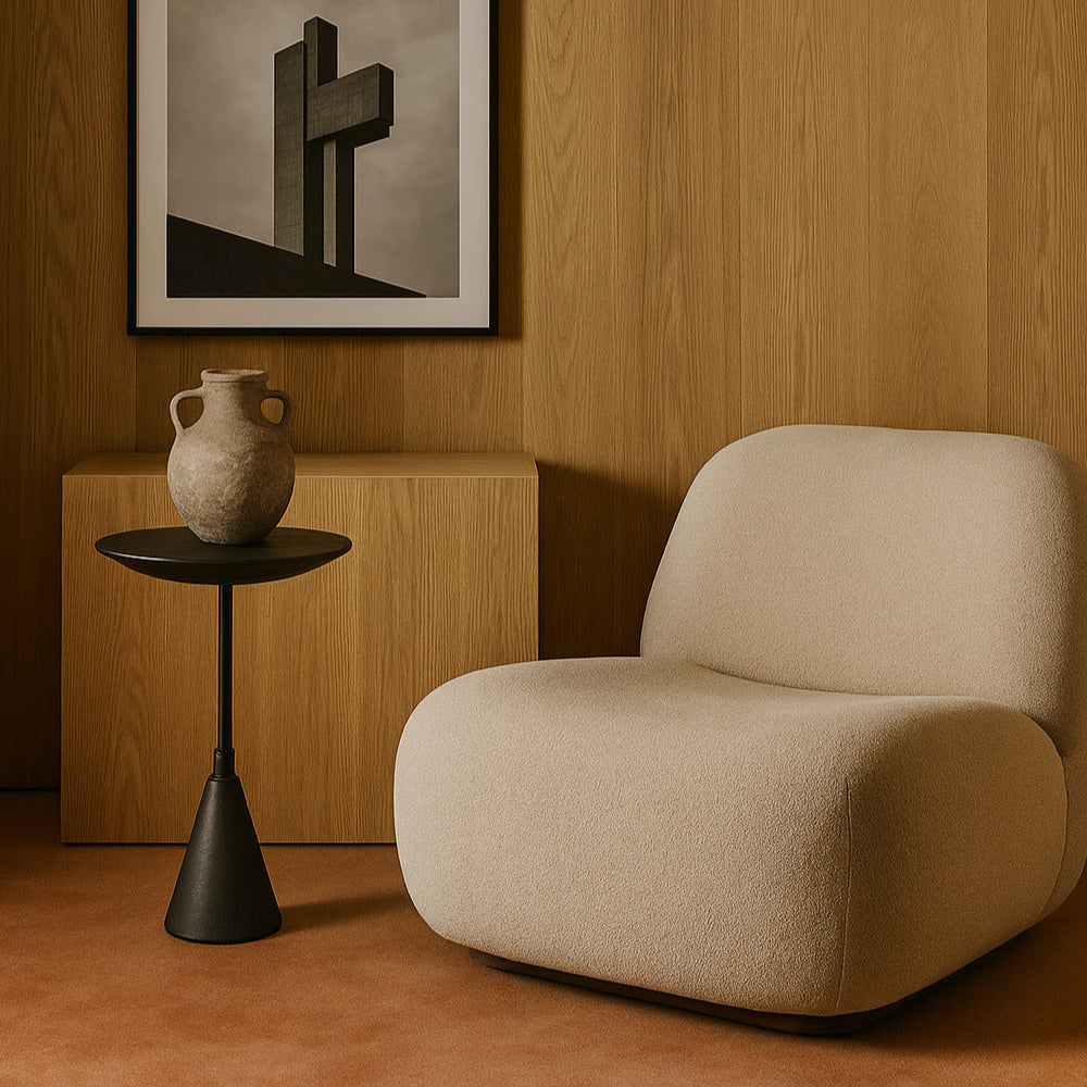 Beige armchair in a room with wooden walls, a side table, and framed artwork.