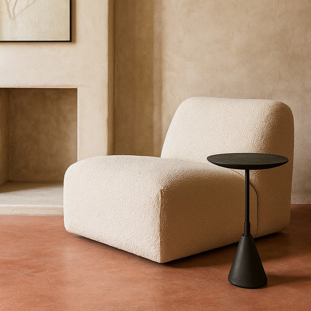 Beige armchair and black side table against a beige wall