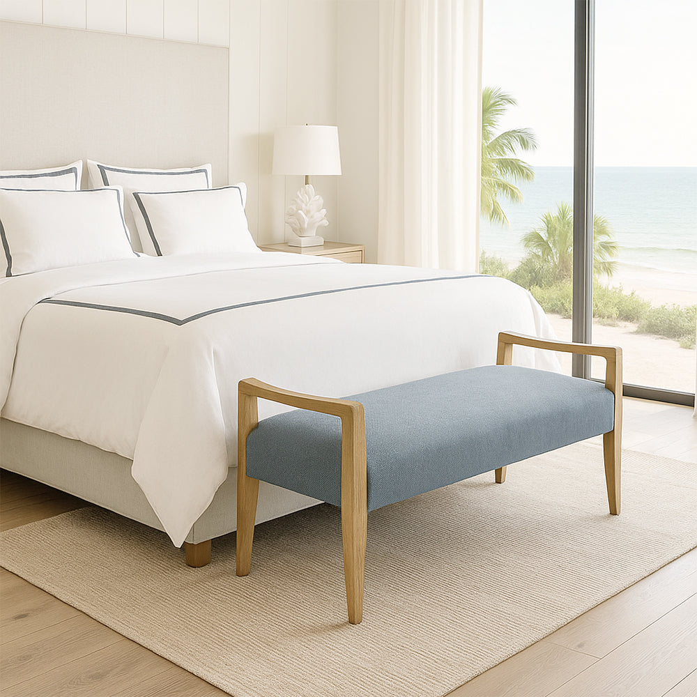 Bedroom with a bed, blue bench, and ocean view.