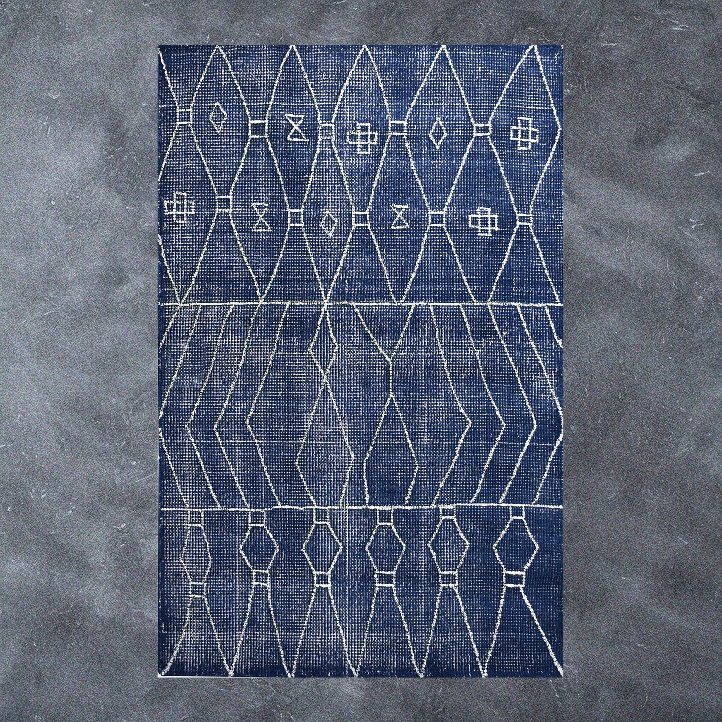 Blue and white geometric rug on concrete.