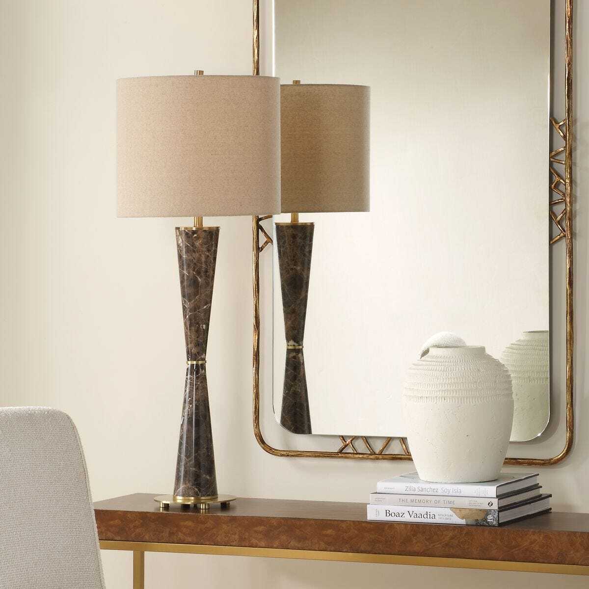 Decorative table lamp with a mirror and books on a console table.