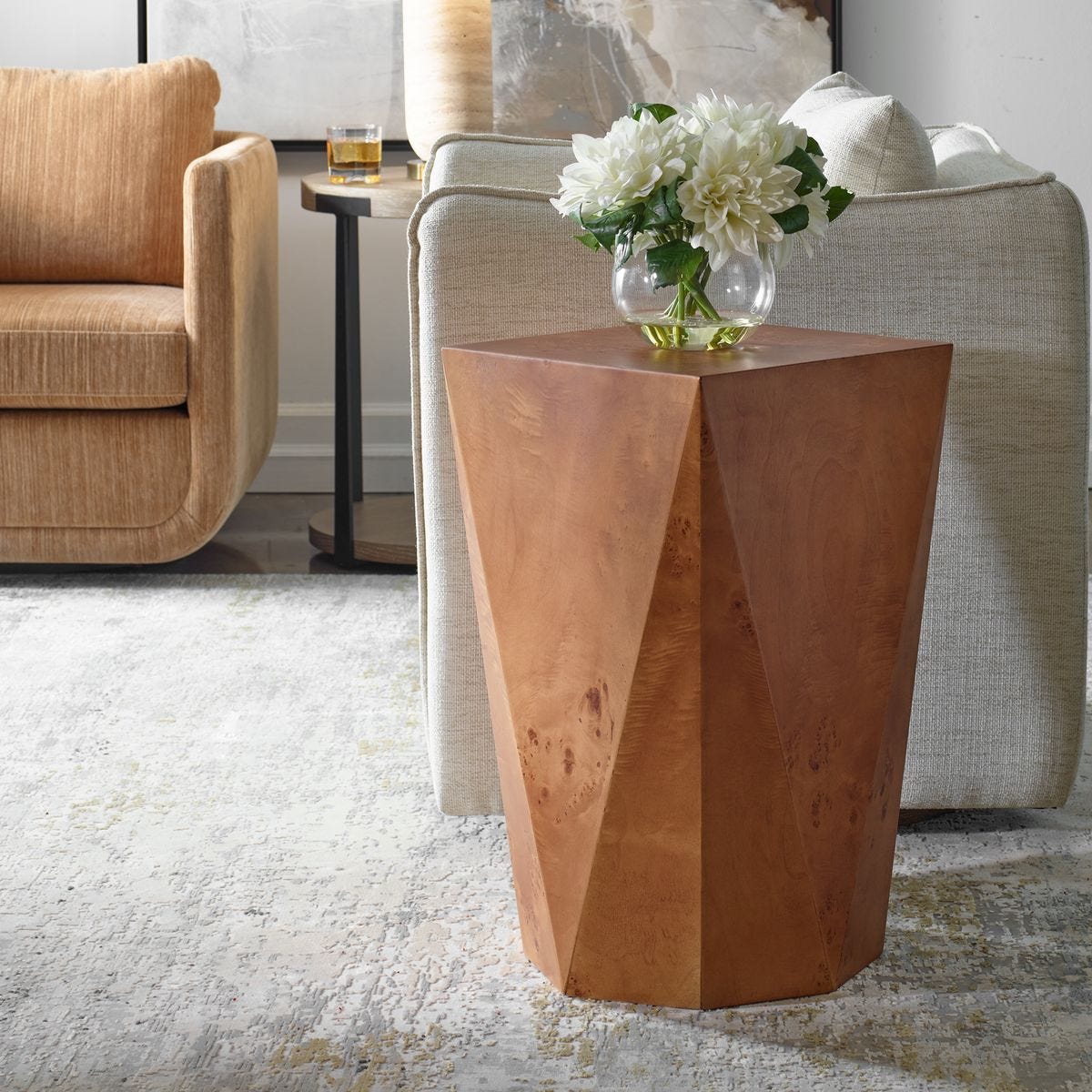 Wooden side table with a vase of white flowers in a living room setting.