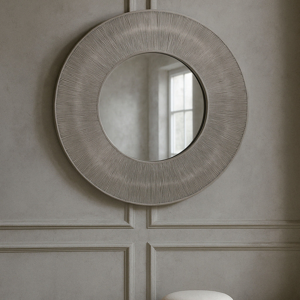 Round decorative mirror on a wall with wicker stools below