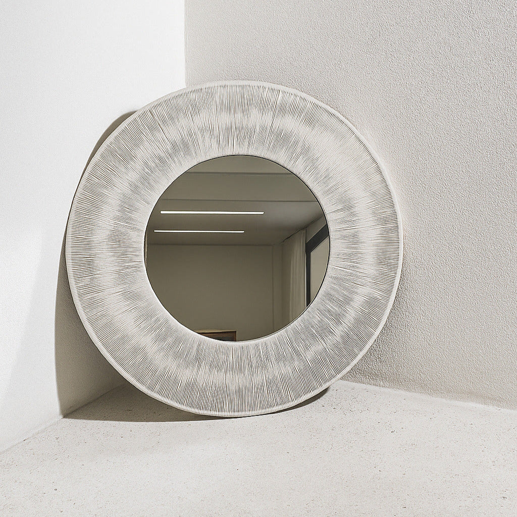 Round textured mirror on a white surface with a neutral background