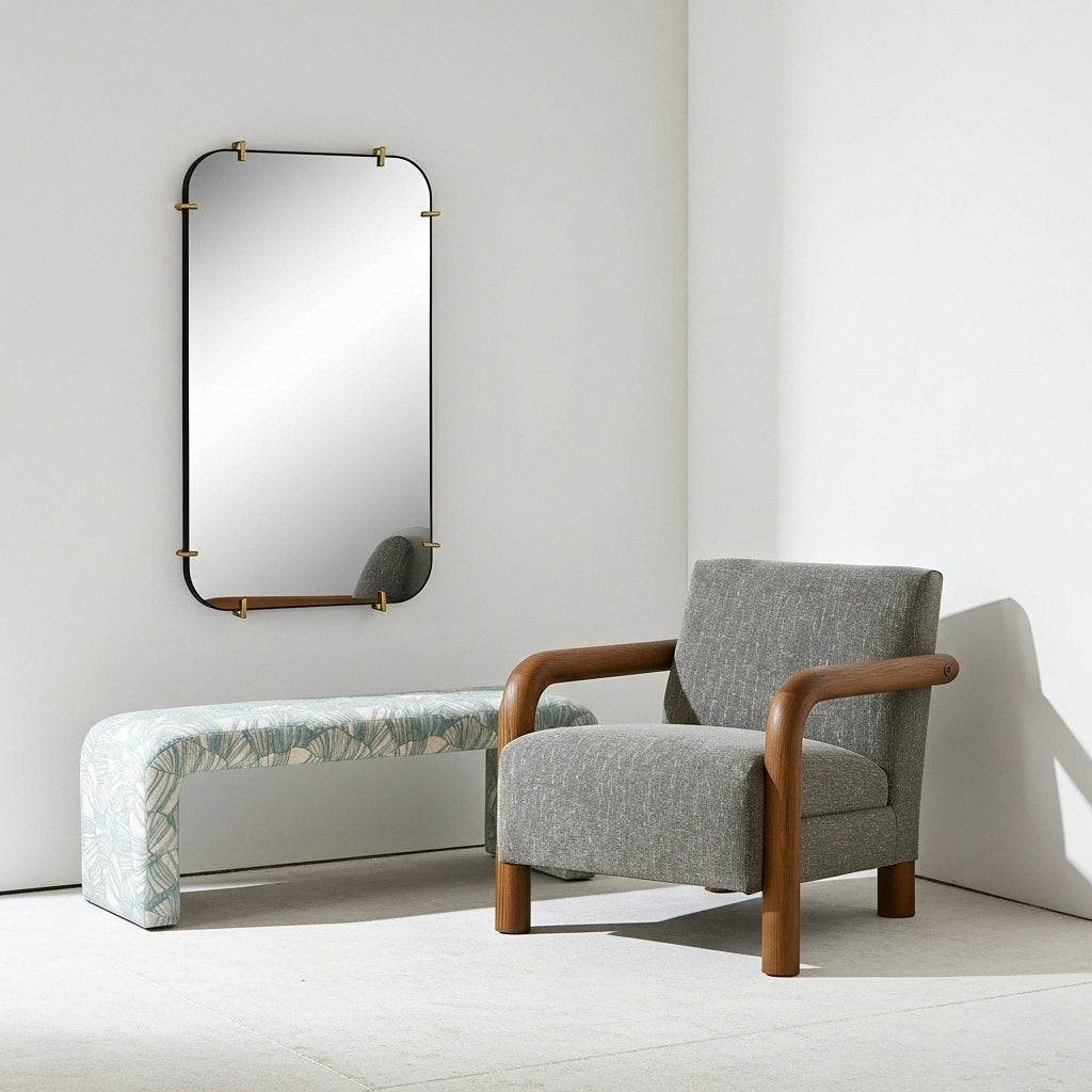 Gray armchair with wooden arms and legs in a minimalistic room with a mirror and bench.
