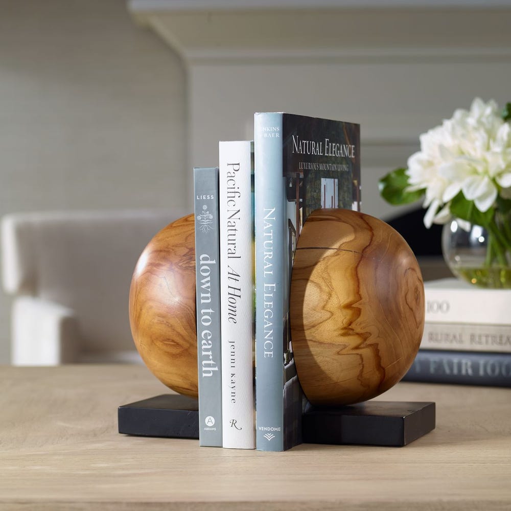 Wooden orb bookends holding books on a wooden surface.
