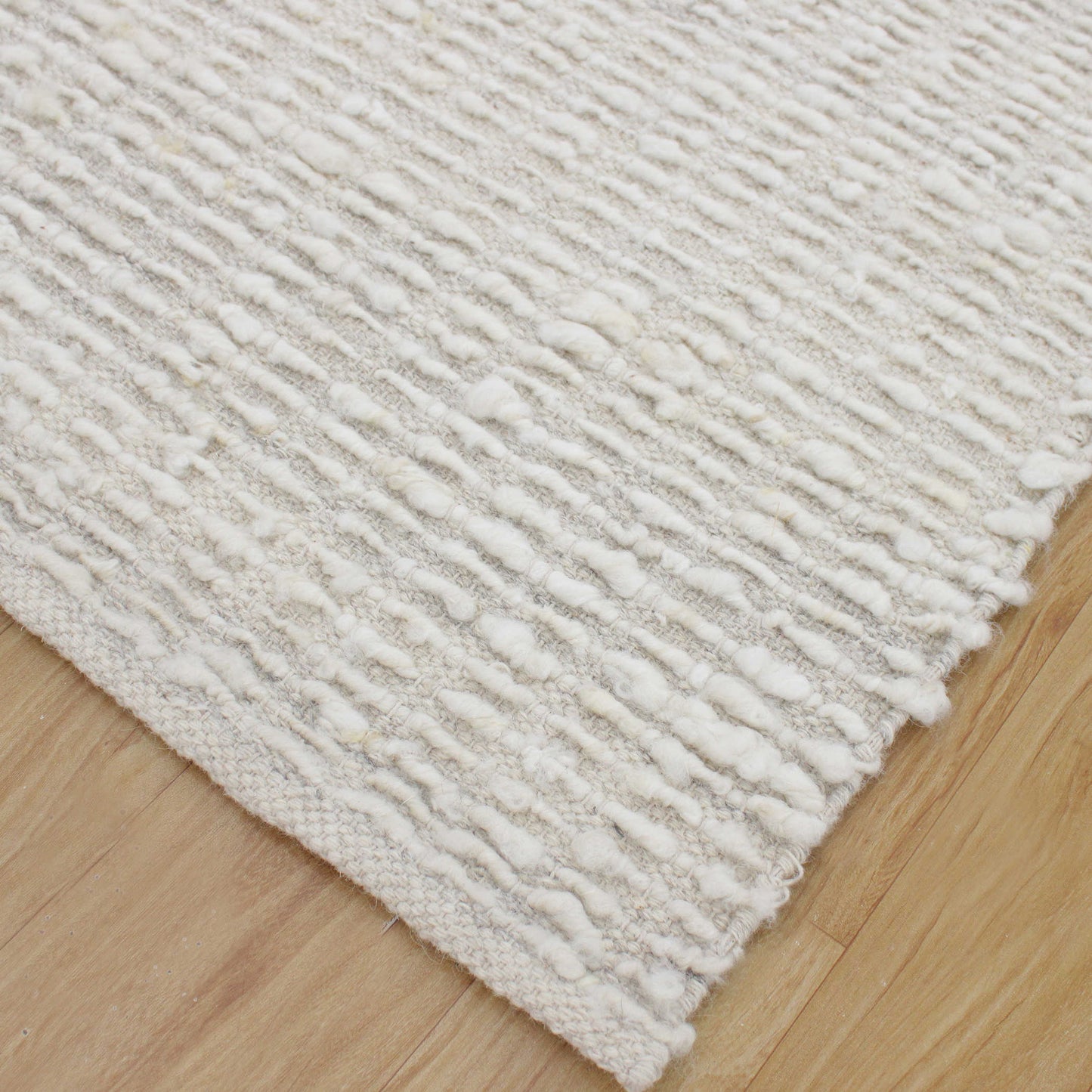 Corner of ivory rug on floor.