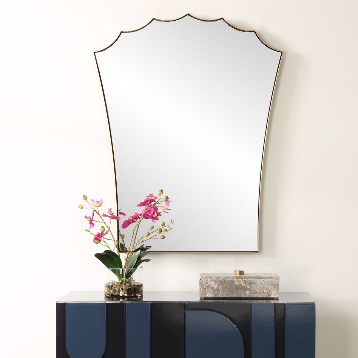 Decorative mirror on a wall above a console table with a plant and box.