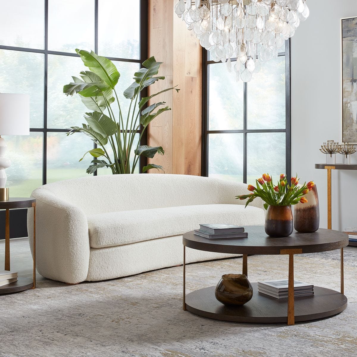 Modern living room with a white sofa, round wooden coffee table, and decorative elements.