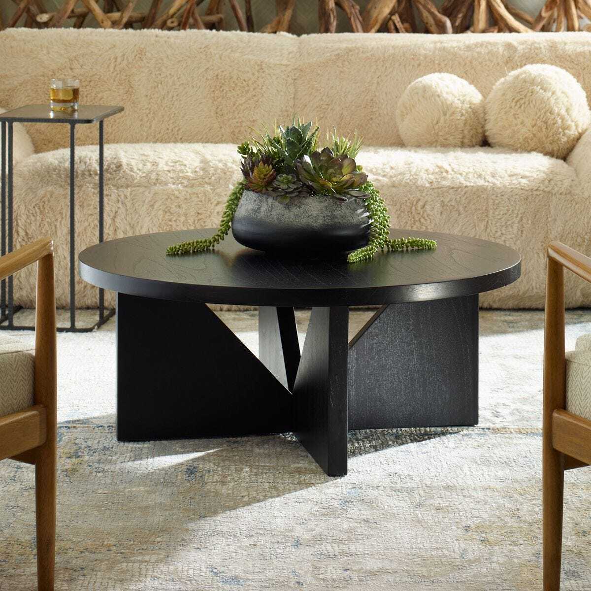 Modern black coffee table with decorative plant in a living room setting