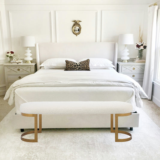 White and gold living room bench with black and white carpet and blue painting.
