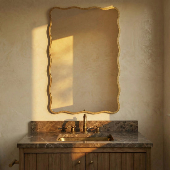 Bathroom vanity with marble countertop and gold-framed mirror on textured wall.