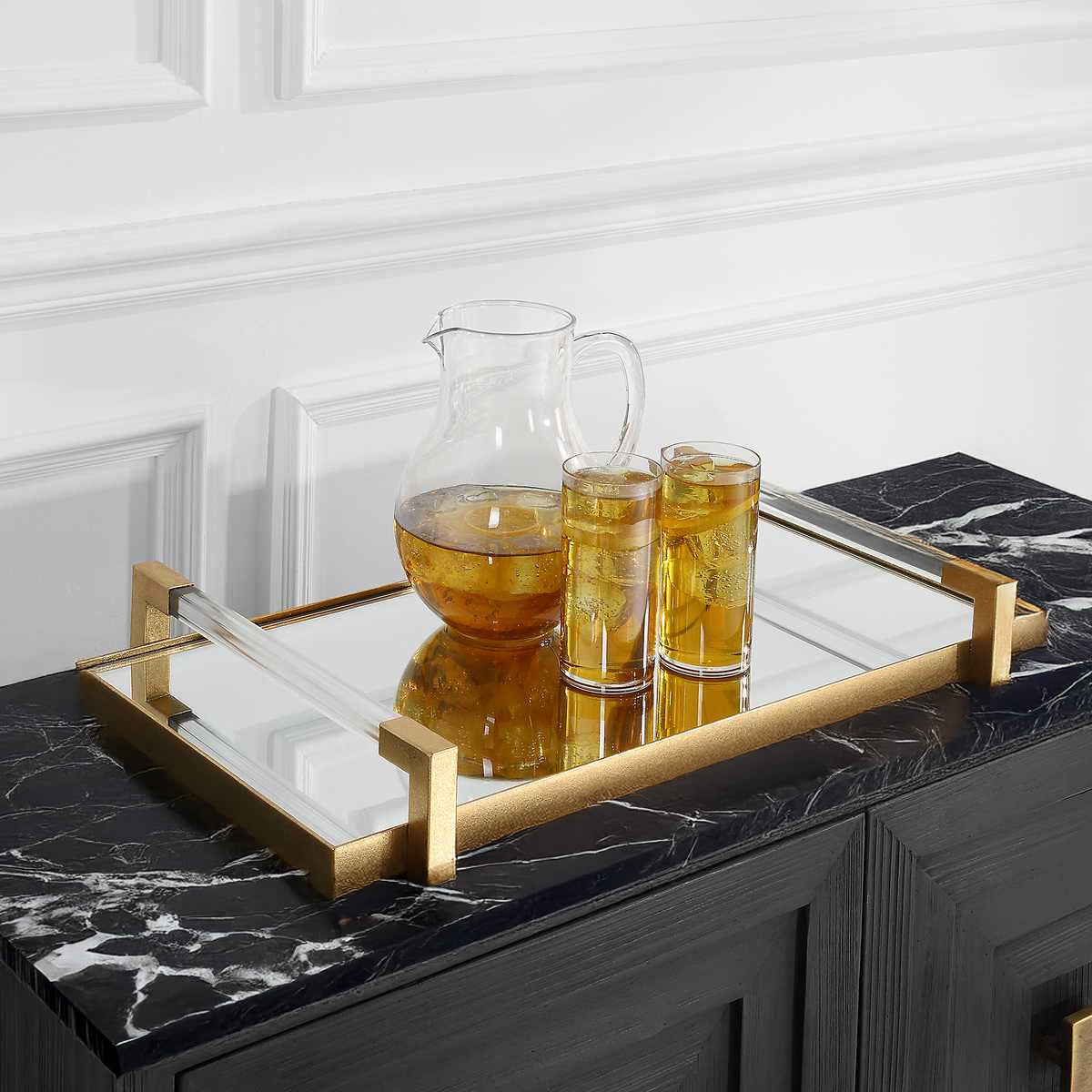 Gold mirrored tray on black marble console table with iced tea.