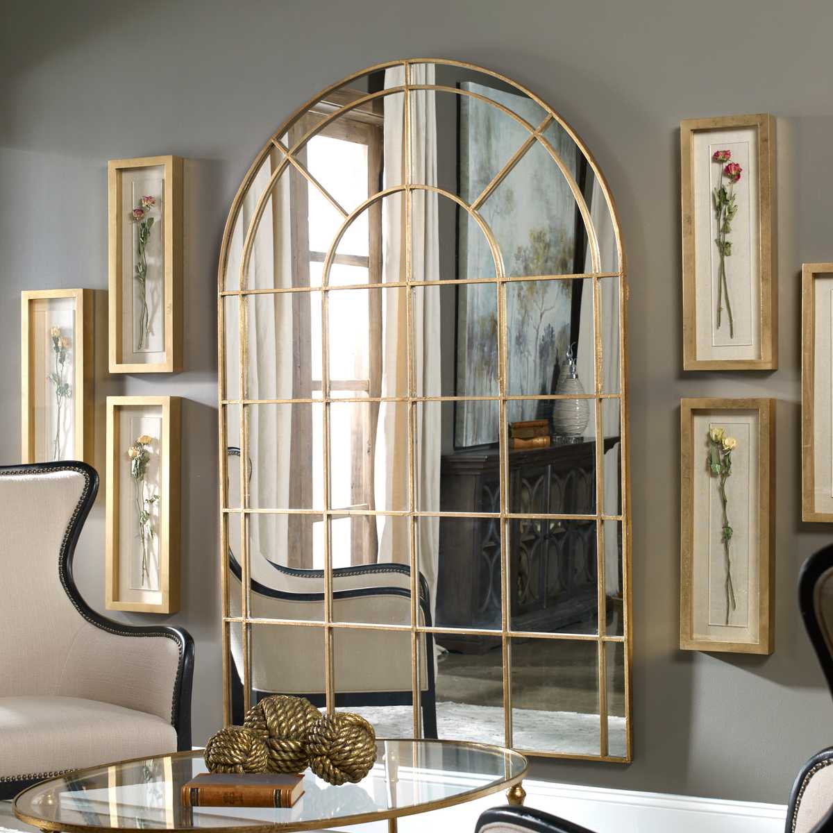 Decorative wall mirror with gold frame in a room with framed pictures on the wall.