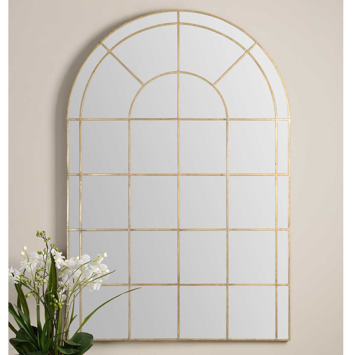 Decorative wall mirror with gold frame on a beige wall