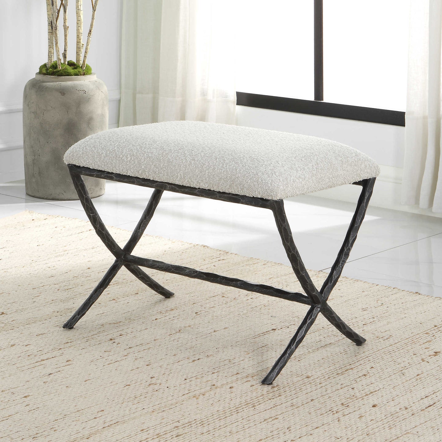 Gray contemporary bench seat in a white living room with ivory rug and concrete planter.
