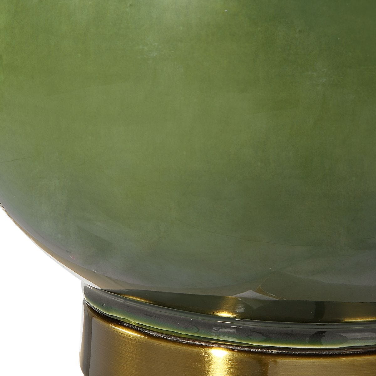 Close-up of a green glass object with a gold base on a white background