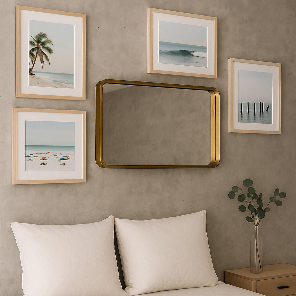 Bedroom with framed beach-themed artwork and a gold mirror on a beige wall.