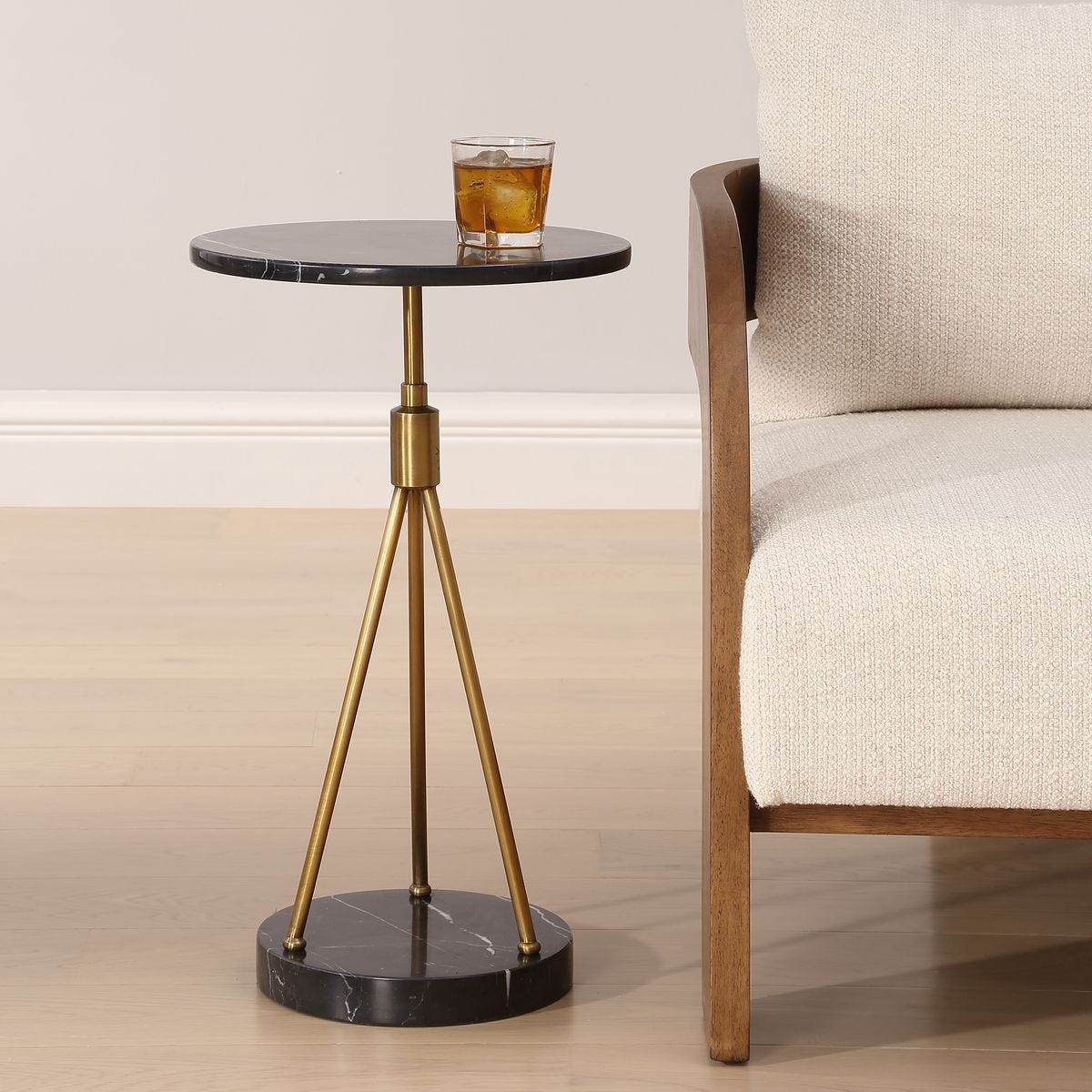 Small round side table with marble top and brass legs next to a beige sofa.