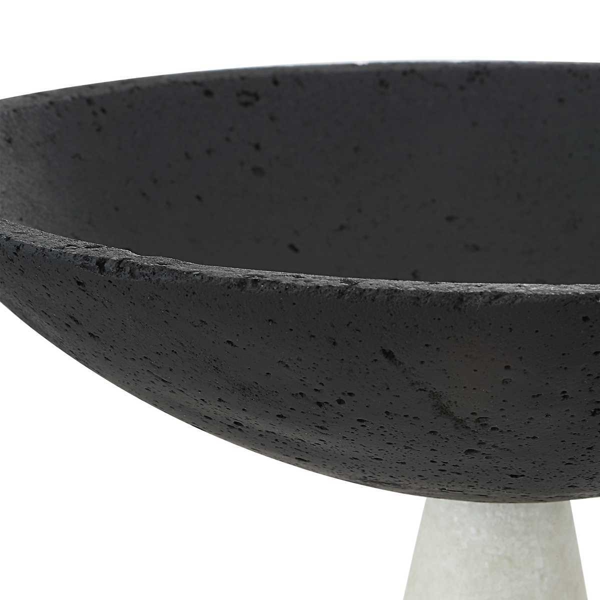 Black concrete bowl on a white pedestal against a white background