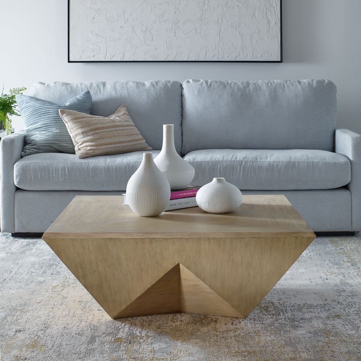Modern living room with a gray sofa, wooden coffee table, and decorative vases.