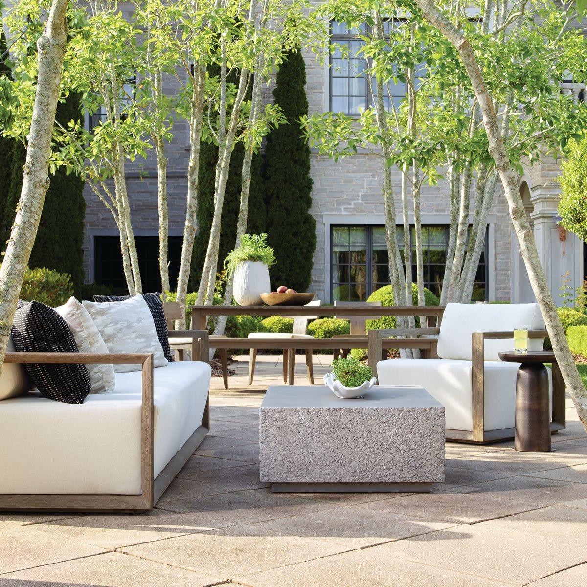 Outdoor patio with modern furniture, trees, and a building in the background
