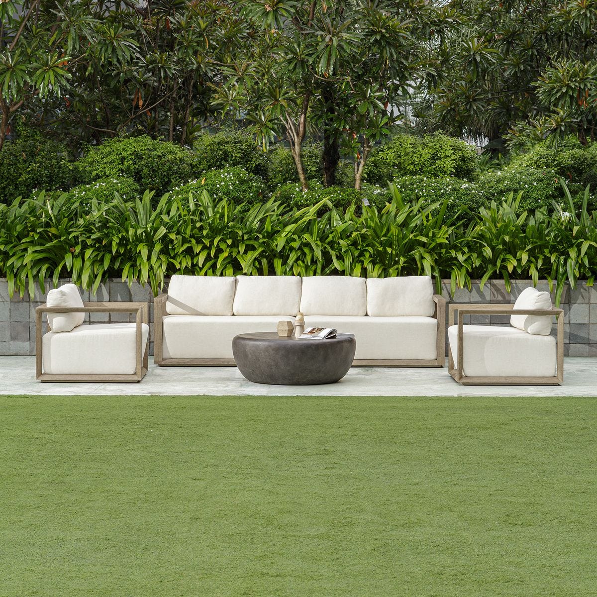 Outdoor furniture set with a sofa, chairs, and coffee table in a garden setting.