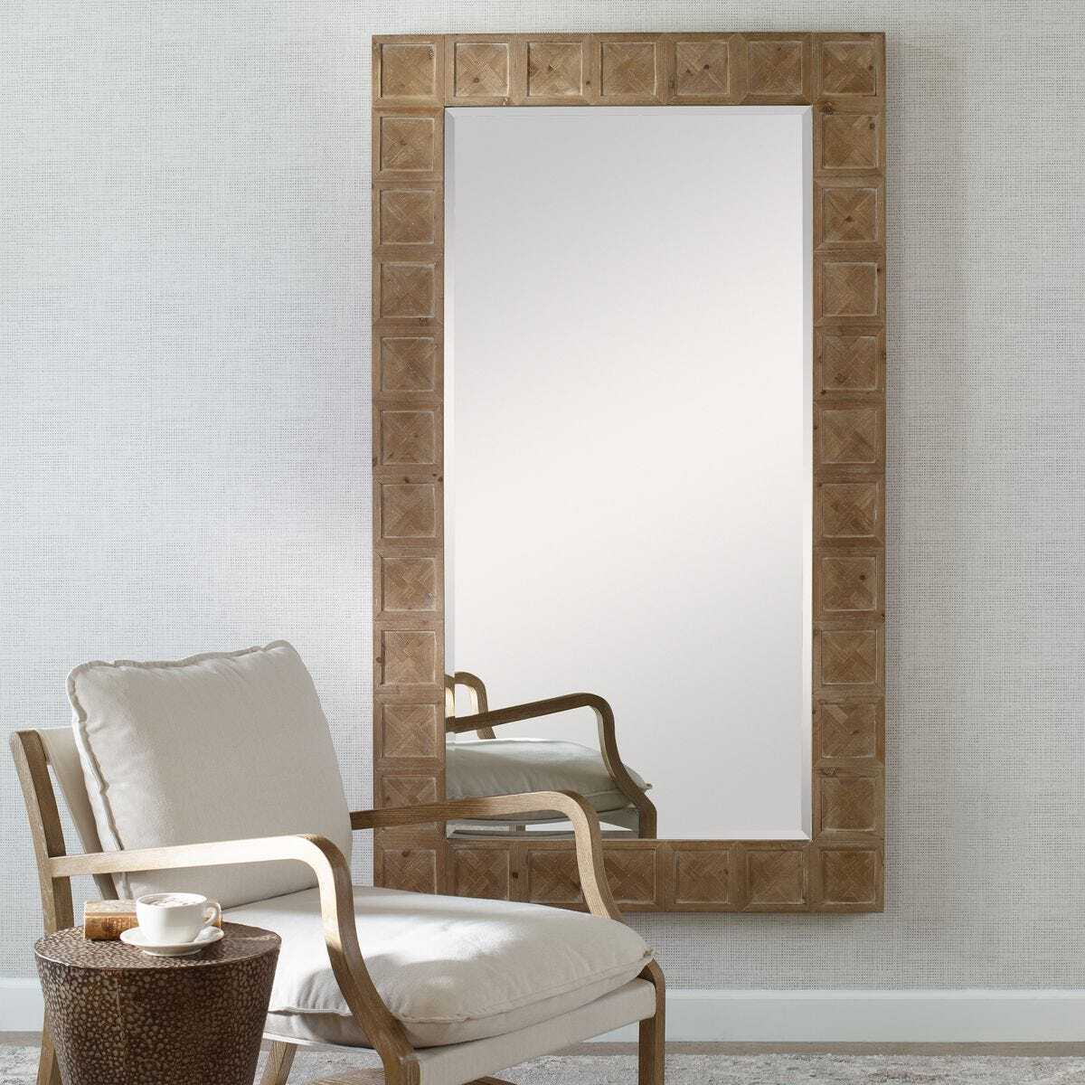 Wooden-framed mirror on a wall with a chair and small table in the foreground.