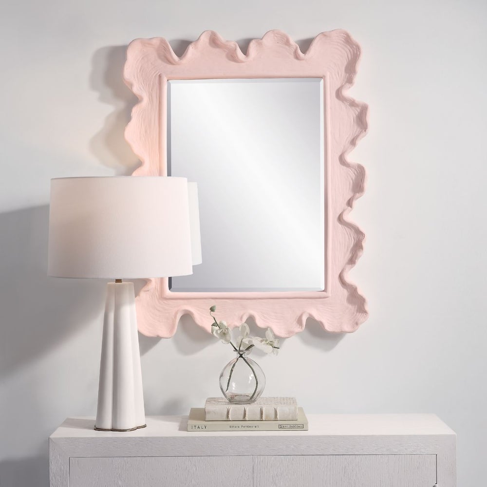 Pink wall mirror above dresser.