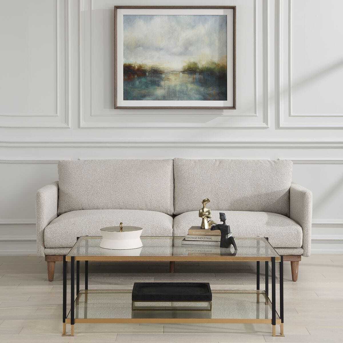 Living room with a beige sofa, glass coffee table, and wall art.