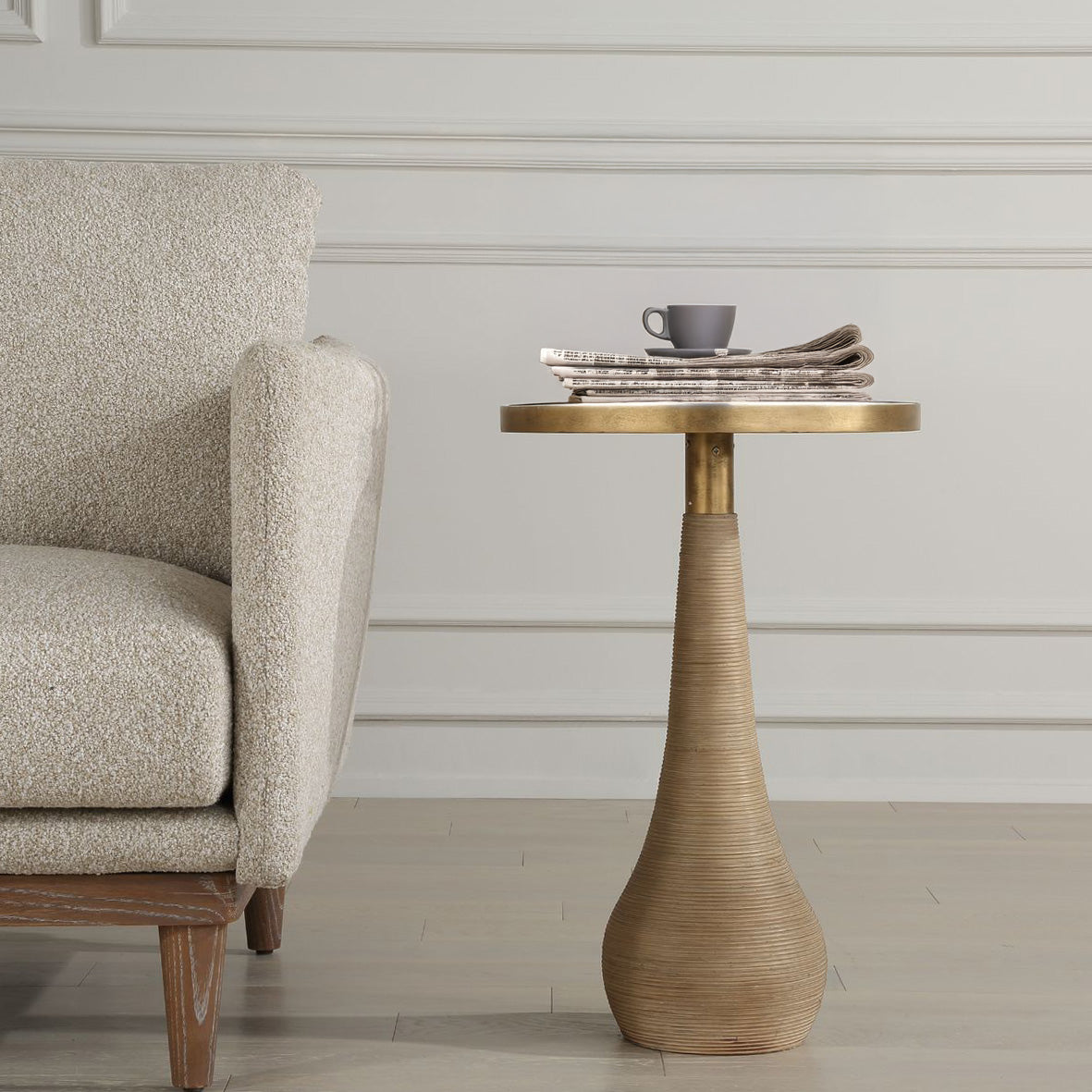 Rattan end table with coffee on top and decorative armchair in living room.