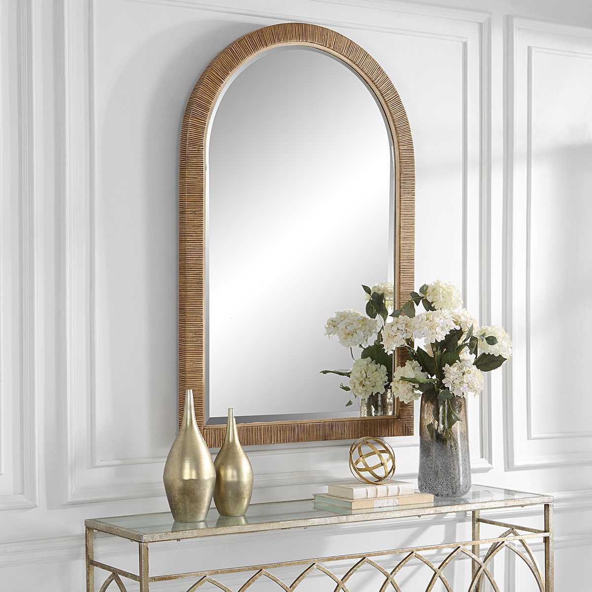 Decorative mirror with rattan frame on a wall above a console table with decorative items.
