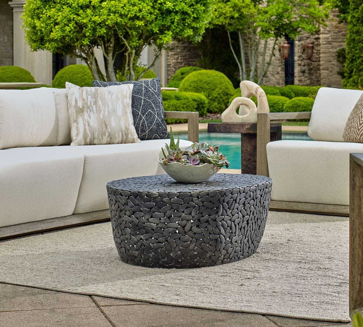 Outdoor patio setting with a stone coffee table and white sofa.