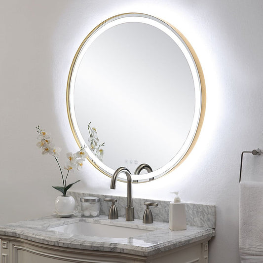 Lighted round gold mirror over a marble vanity.