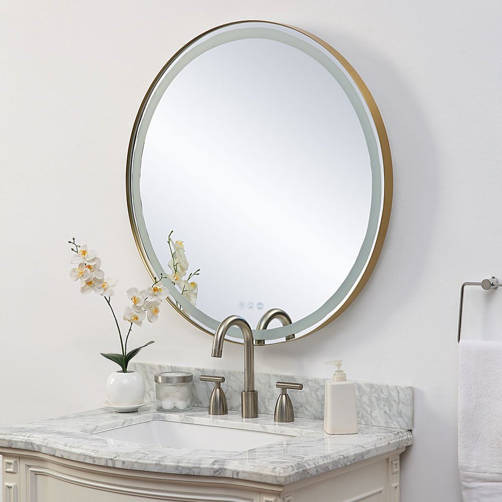 Angled Lighted round gold mirror over a marble vanity.