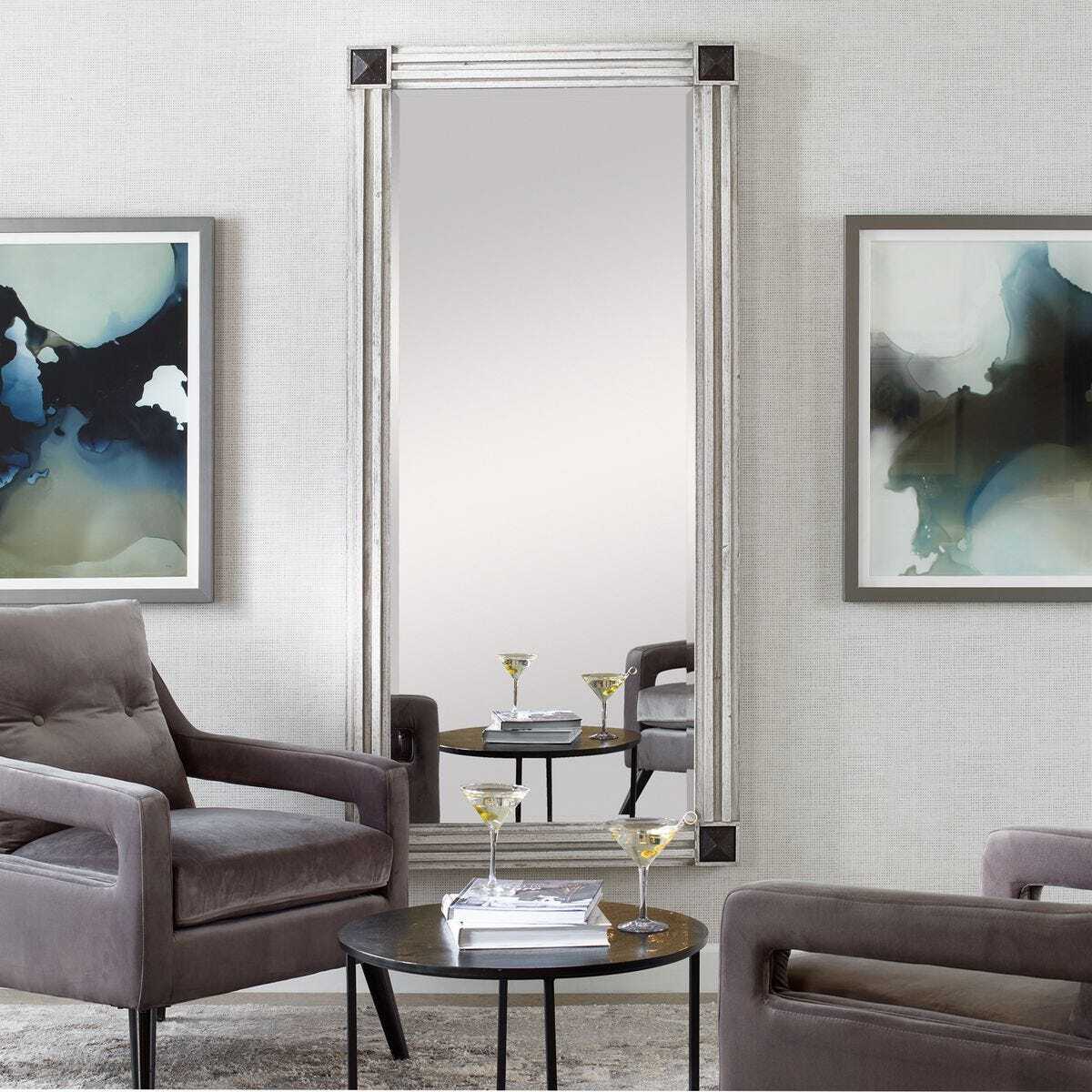 Modern living room with gray chairs, a round table, and abstract art on the walls.