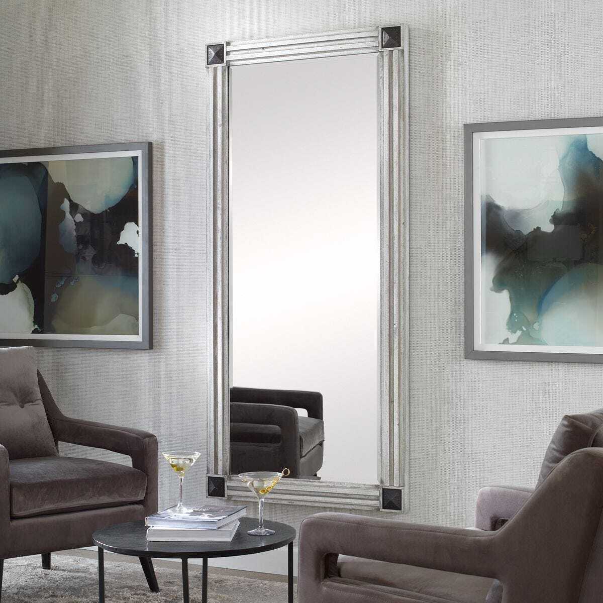 Living room with gray sofa, round coffee table, and large mirror on the wall.