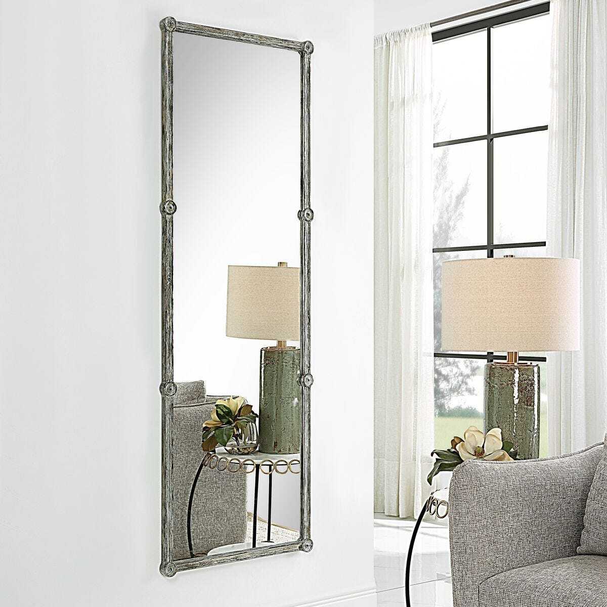 Decorative mirror with a shelf in a room with a lamp and window.